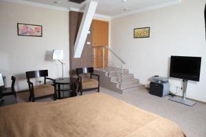 ein Hotelzimmer mit einem Bett, einem TV und einer Treppe in der Unterkunft Lavina Hotel in Dnipro