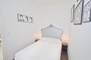 uma cama branca num quarto com fotografias na parede em PROMENADE HOLIDAY - PALATIN & SEA em Nice