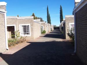 an alley of brick houses with trees on both sides at Gables Inn in Colesberg
