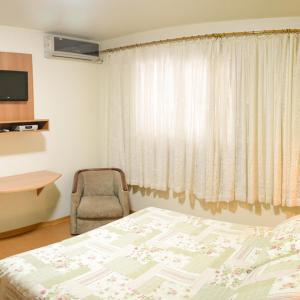 a bedroom with a bed and a chair and a window at Pampa Hotel in Vacaria