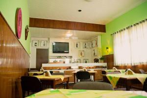a restaurant with green walls and tables and chairs at Pampa Hotel in Vacaria