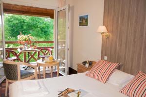 1 dormitorio con 1 cama y balcón con mesa en Les Trois Soleils en Saint-Céré
