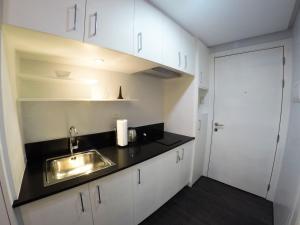 a kitchen with white cabinets and a sink and a door at Riganna Two @ Shell Residences - near Airport, MOA in Manila