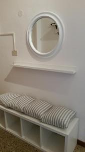 a mirror on a white wall with a bench with a mirror at In Vacanza da Marinella in Albenga