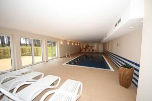 a swimming pool with white chairs in a room at Haus Meeresblick A 2 23 Silberdistel mit Balkon in Baabe