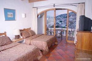 a hotel room with two beds and a balcony at Posada de la Mision, Hotel Museo y Jardin in Taxco de Alarcón