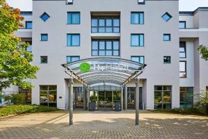 une vue extérieure d'un bâtiment avec un panneau vert recyclé dans l'établissement H+ Hotel Hannover, à Hanovre