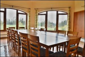 a large table and chairs in a room with windows at Penzion Starý dvůr in Nové Dvory