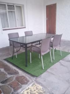 a black table and chairs on a green rug at White House Lodge On Main in Beaufort West