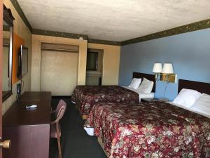 a hotel room with two beds and a desk at Deluxe Inn Kilgore in Kilgore +10 photos