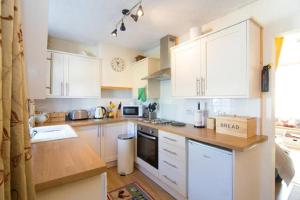 a kitchen with white cabinets and a counter top at Crinan Canal Cottage in Lochgilphead