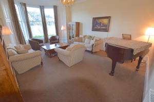 a living room with a grand piano and chairs at Beach House - Carrick Castle in Carrick