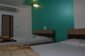 a bedroom with two beds and a green wall at Hotel Pariwar in Aurangabad