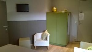 a room with a white chair and a green cabinet at B&B De Zoete Kers in Wakken