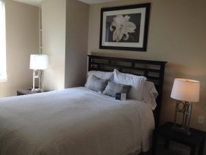 a bedroom with a bed with white sheets and two lamps at National at Ballston Metro in Arlington
