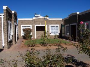 a brick building with white doors and a courtyard at Gables Inn in Colesberg