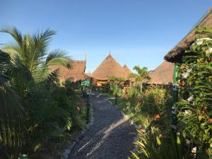 瑪哈沙拉堪府的住宿－The Orchid Resort & Relax，穿过茅草屋顶的村庄的路径
