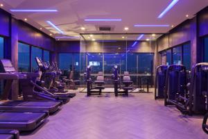 einen Fitnessraum mit einer Reihe von Trainingsgeräten und Fenstern in der Unterkunft One Residence Hotel & Apartment in Phnom Penh