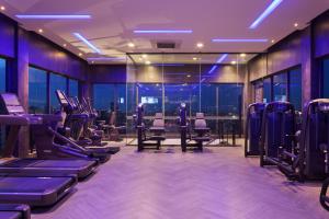a gym with rows of exercise equipment and windows at One Residence Hotel & Apartment in Phnom Penh