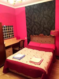 Valera Homestay في تبليسي: غرفة نوم مع سرير بجدران وردية ومكتب