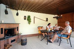 eine Familie, die an einem Tisch auf einer Terrasse mit einem Kamin sitzt in der Unterkunft Ferienwohnungen Neuner in Plankenfels