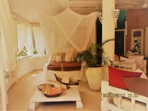 a bedroom with a bed with curtains and a table at Fortamu Lady D House Watamu in Watamu