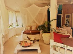 a bedroom with a bed with curtains and a table at Lady D House in Watamu