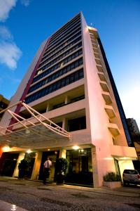 a tall building with people walking in front of it at Rede Andrade LG Inn in Recife
