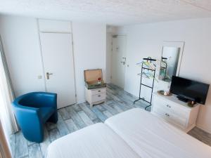 een slaapkamer met een bed en een blauwe stoel en een tv bij Stadshotel de Graafschap in Doetinchem