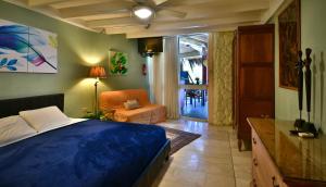 een slaapkamer met een blauw bed, een stoel en een raam bij Beach House Aruba Apartments in Palm-Eagle Beach