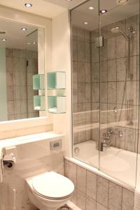 a bathroom with a toilet and a shower and a sink at Mercure Hotel Dortmund Centrum in Dortmund
