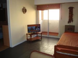 1 dormitorio con 1 cama, TV y mesa en Departamento Atenas en Mar del Plata