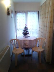 ein Tisch mit einem Weihnachtsbaum darauf mit zwei Stühlen in der Unterkunft Pensiunea Pinul Negru in Băile Herculane