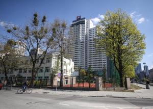 uma pessoa a andar de bicicleta numa rua com um edifício alto em Eden Apartment Łucka em Varsóvia