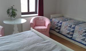 ライプツィヒにある3 Raum Ferienwohnung in Leipzig 2 km vom Stadtzentrum entferntのベッドルーム1室(ベッド2台、ピンクの椅子、テーブル付)