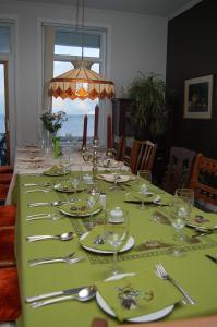 a long table with a green table cloth and silverware at Gite les 2 Soeurs in Roberval