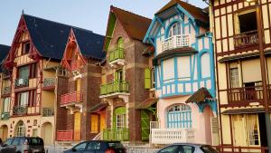 eine Reihe bunter Häuser mit davor geparkten Autos in der Unterkunft la villa mersoise in Mers-les-Bains