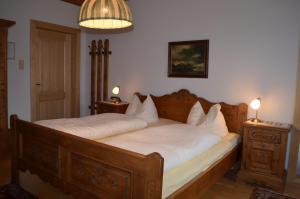 Un dormitorio con una gran cama de madera con sábanas blancas. en "Kaiser Karl" *** Ferienwohnungen en Grossgmain