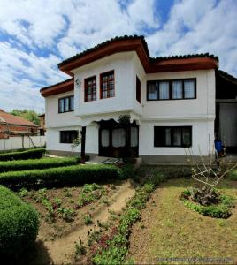 a white house with red windows in a yard at Bujtina Zhaveli in Gjakove