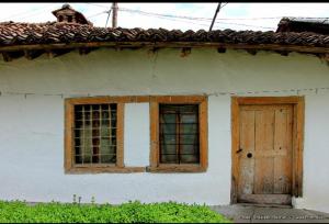 a white house with a wooden door and windows at Bujtina Zhaveli in Gjakove