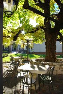 un groupe de tables et de chaises sous un arbre dans l'établissement Dependance Lipa, à Basovizza