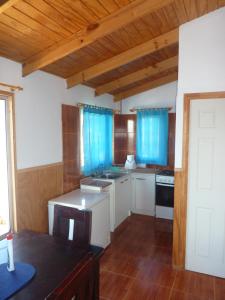 una cocina con armarios blancos y cortinas azules en Cabaña Ecológica Trotamundos, en Coquimbo