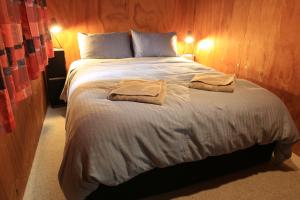 a bedroom with a large bed with two towels on it at Earthbridge in Hikutaia