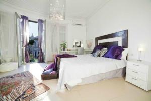 ein weißes Schlafzimmer mit einem großen Bett mit lila Kissen in der Unterkunft Balcones y Vistas en el Centro de la Ciudad in Barcelona