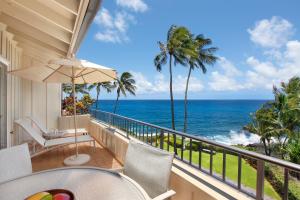 a balcony with a table and chairs and the ocean at Whalers Cove in Poipu in Koloa