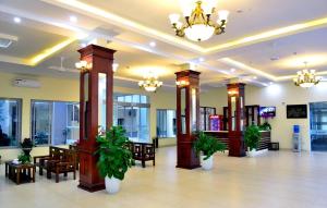 eine Lobby mit Tischen, Stühlen und Topfpflanzen in der Unterkunft Hanvet Hotel Do Son in Ðố Sơn