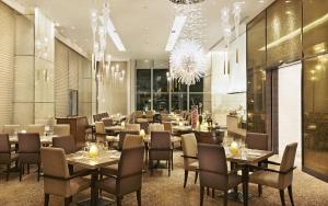 Un restaurante con mesas y sillas y una lámpara de araña. en Fairmont Makati, en Manila