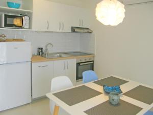 Una cocina con una mesa y un refrigerador blanco. en Apartments Mare, en Primošten