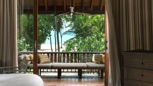 a bedroom with a balcony with a bed and a window at Four Seasons Resort Langkawi in Tanjung Rhu