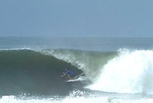 a man riding a wave on a surfboard in the ocean at Hotel Caleta in San Miguel